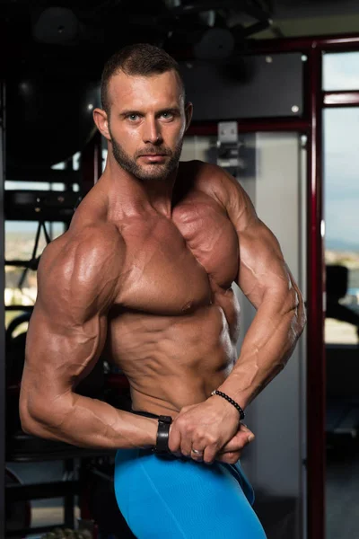 Hombre musculoso guapo flexionando músculos en el gimnasio — Foto de Stock