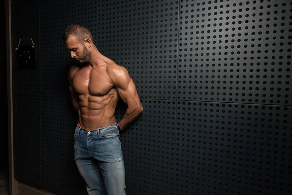 Modelo de pie fuerte contra una pared posando — Foto de Stock