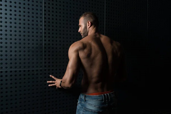 Modell som flexar muskler mot väggen — Stockfoto