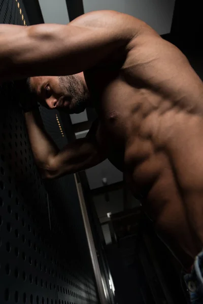 Retrato de un hombre musculoso parado cerca de la pared — Foto de Stock