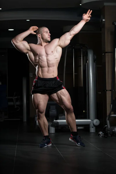 Biceps pose d'un jeune homme dans la salle de gym — Photo