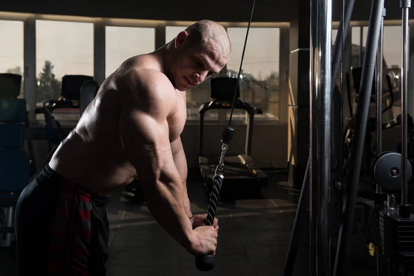 Kulturista dělat těžké cvičení pro Triceps s kabelem — Stock fotografie