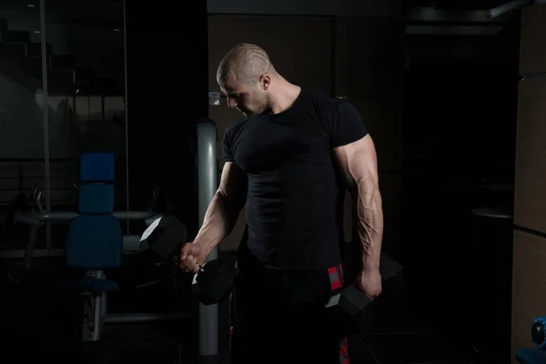 Exercício de bíceps com halteres em um ginásio — Fotografia de Stock