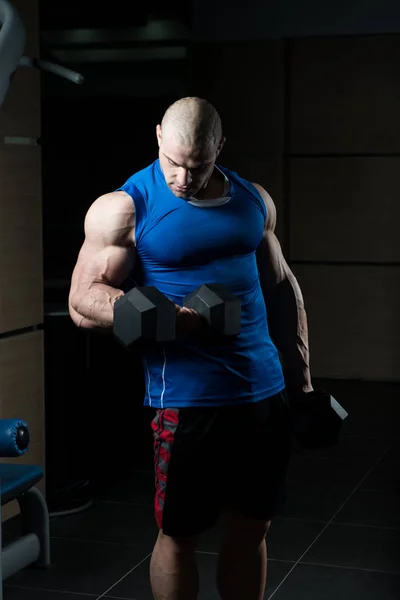 Kulturista cvičení biceps s činkami — Stock fotografie