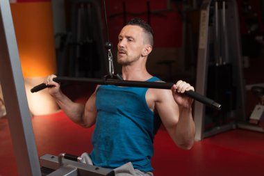 Arka üstünde makine içinde jimnastik salonu için ağır egzersiz yaparak yakışıklı sporcu