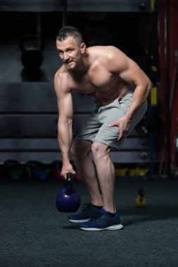 Genç adam su ısıtıcısı çan karanlık bir spor salonu - su ısıtıcısı-bell ile ağır egzersiz yapmak Bodybuilder olan çalışma dışarı