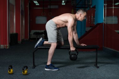 Genç adam su ısıtıcısı çan karanlık bir spor salonu - su ısıtıcısı-bell ile ağır egzersiz yapmak Bodybuilder olan çalışma dışarı