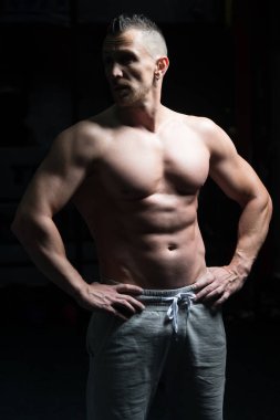 Yakışıklı Genç Adam Spor Salonunda Güçlü Duruyor ve Kaslarını Geriyor - Kas Atletik Vücut Geliştirici Spor Sonrası Spor Pozisyonu