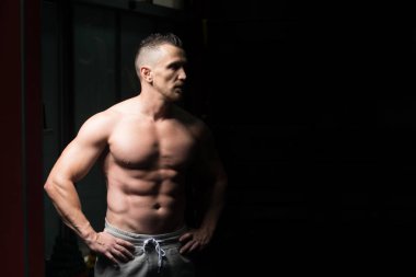 Spor salonu ve kasların esneme - güçlü ayakta sağlıklı genç adam kaslı atletik vücut Fitness Model çalışmaları sonra poz