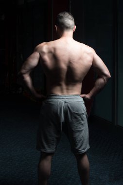 Yakışıklı Genç Adam Spor Salonunda Güçlü Duruyor ve Kaslarını Geriyor - Kas Atletik Vücut Geliştirici Spor Sonrası Spor Pozisyonu