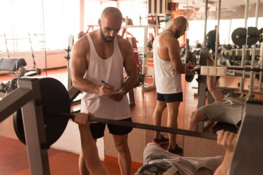 Kişisel eğitmen gösteren genç adam nasıl tren göğüs egzersiz Ile Barbell Içinde A Sağlık ve fitness Concept
