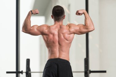 Spor salonu ve kasların esneme - güçlü ayakta sağlıklı genç adam kaslı atletik vücut Fitness Model çalışmaları sonra poz