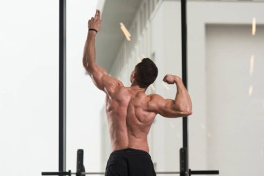 Yakışıklı Genç Adam Spor Salonunda Güçlü Duruyor ve Kaslarını Geriyor - Kas Atletik Vücut Geliştirici Spor Sonrası Spor Pozisyonu