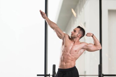 Yakışıklı Genç Adam Spor Salonunda Güçlü Duruyor ve Kaslarını Geriyor - Kas Atletik Vücut Geliştirici Spor Sonrası Spor Pozisyonu