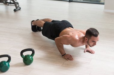 Spor salonunda Kettle Bell 'le şınav çeken sağlıklı bir sporcu. Kettle Bell Egzersizi.
