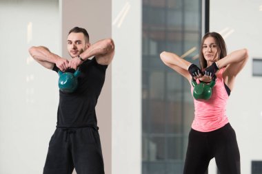 Genç kadın ve adam su ısıtıcısı çan bir spor salonu - su ısıtıcısı çan egzersiz ile çalışma