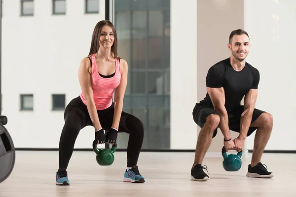 健身女人和男人用水壶钟在健身房 壶铃锻炼工作 — 图库照片