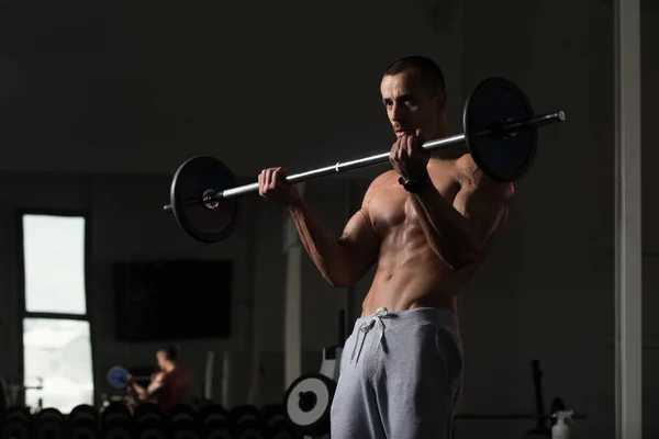 在健身房锻炼二头肌杠铃与男人 — 图库照片