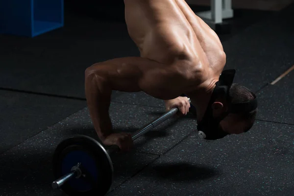 Athlète exercice push-ups sur haltère en altitude masque — Photo