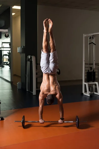 Sportler übt Handstand-Liegestütze an der Langhantel im Fitnessstudio — Stockfoto