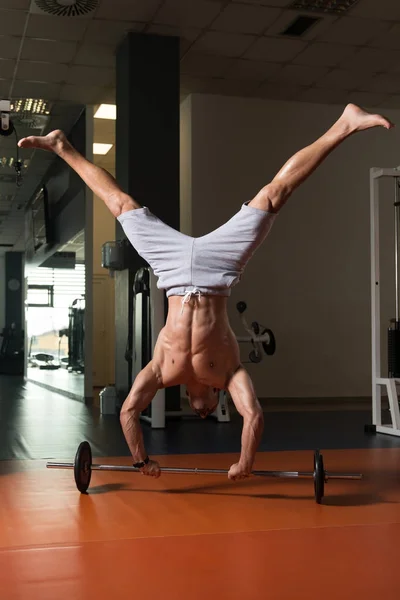 Sportowiec, wykonując Handstand pompki na sztangę w siłowni — Zdjęcie stockowe