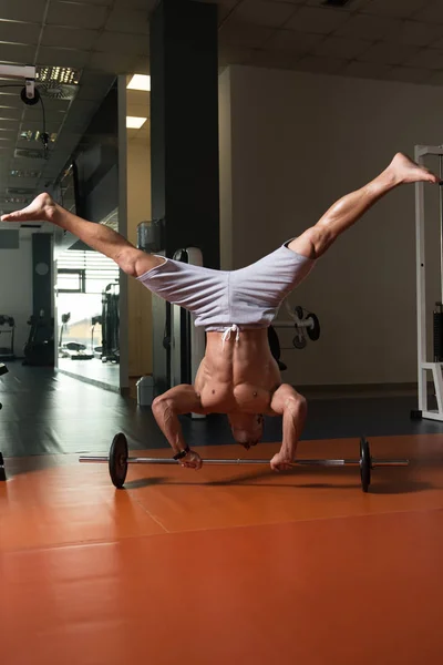 Mann übt Handstand-Liegestütze an Langhantel im Fitnessstudio — Stockfoto