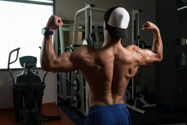 Uomo muscolare che flette i muscoli in palestra — Foto Stock