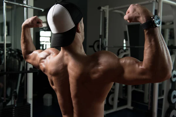 Hombre musculoso guapo flexionando músculos en el gimnasio —  Fotos de Stock