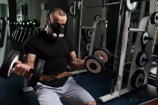 Culturista ejercitando bíceps con sombrillas en máscara de elevación —  Fotos de Stock
