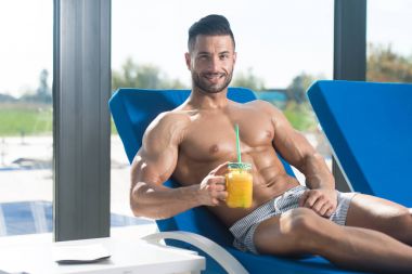 Elinde bir bardak portakal suyu tutan adam.