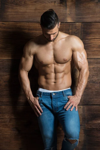 Modelo de pie fuerte contra una pared de madera posando — Foto de Stock