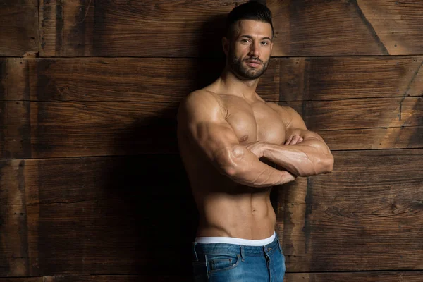 Model Flexing Muscles Near the Wooden Wall — Stock Photo, Image