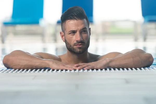 Muž odpočívající uvolnil na okraji bazénu — Stock fotografie