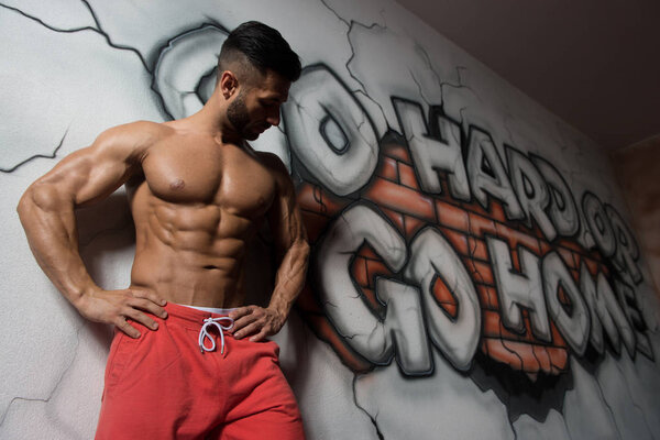 Muscular Man Flexing Muscles At Graffiti Wall