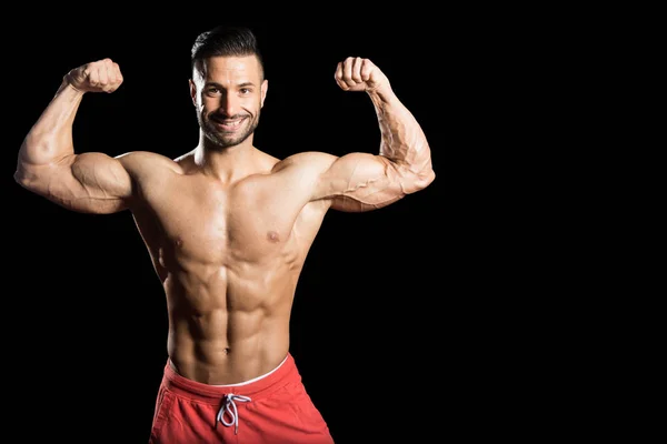 Unga bodybuilder böjning muskler isolera på svart blackground — Stockfoto