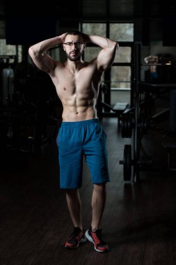 Spor salonunda ayakta ciddi vücut geliştirmeci giyen gözlük