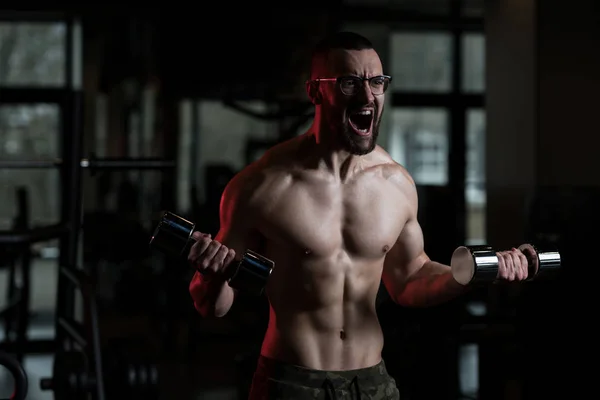 Geek hombre con mancuerna ejercicio bíceps — Foto de Stock