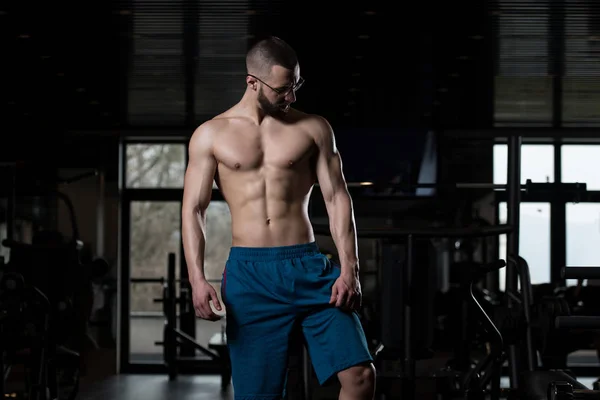 Serious culturista usando gafas de pie en el gimnasio —  Fotos de Stock