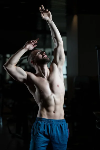 Muž svalnaté Geek protahuje svaly v tělocvičně — Stock fotografie