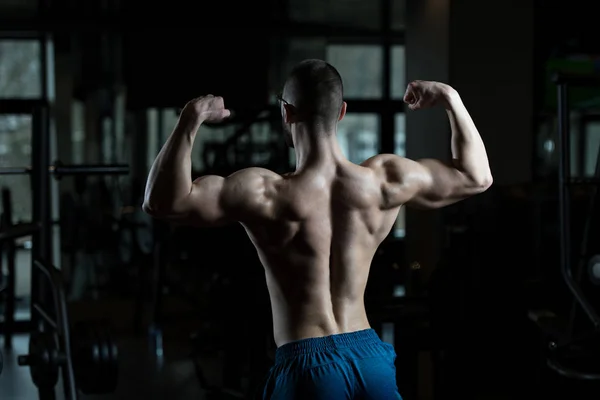 Nerd-Mann steht stark im Fitnessstudio — Stockfoto