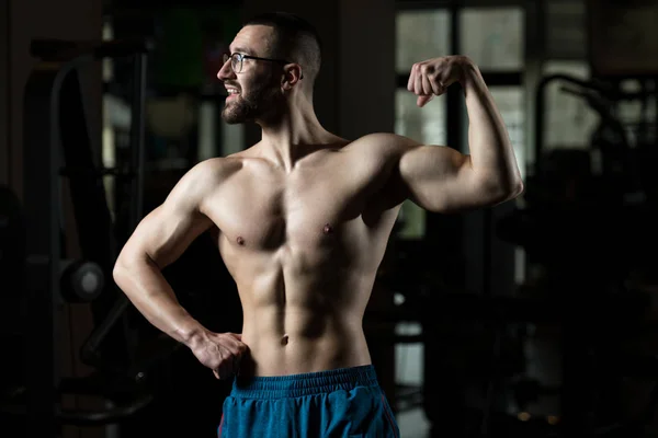 Poważne kulturysta noszenia okularów, stojąc w siłowni — Zdjęcie stockowe