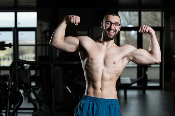 Junge Bodybuilderin mit Brille lässt Muskeln spielen — Stockfoto