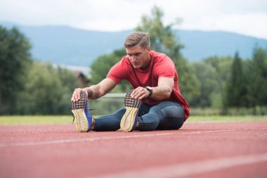 Genç adam atletik egzersiz çalıştırmadan önce germe