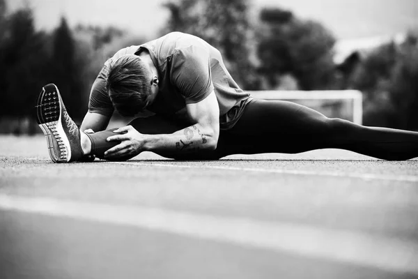 Hombre guapo estiramiento antes de hacer ejercicio fuera de correr — Foto de Stock