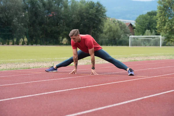 Спортивный бегун делает упражнения на растяжку — стоковое фото