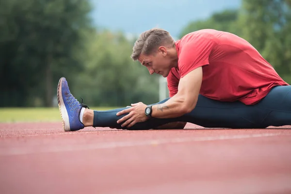 Junger Fitnessmann streckt vor dem Lauf die Beine — Stockfoto