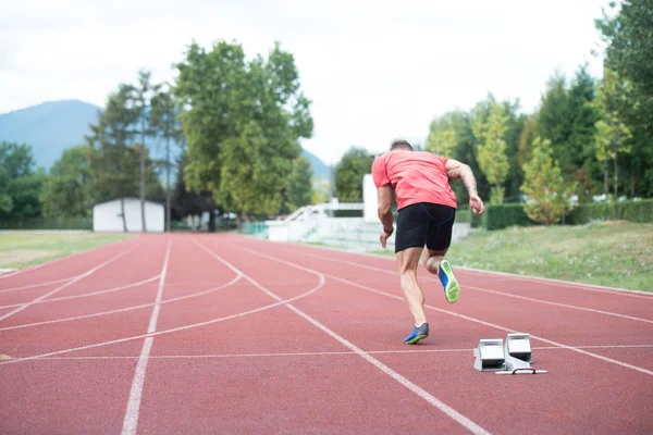 Sprinter pozostawiając bloki startowe na bieżni — Zdjęcie stockowe