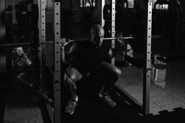Fitness spor salonu içinde bacaklar egzersiz halter kullanan adam