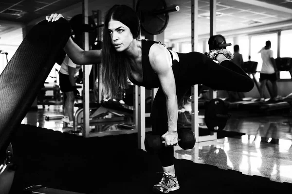 Muskulös kvinna tränar rygg och ben med hantlar — Stockfoto