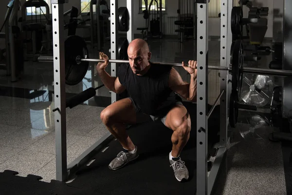 Fitness Man Using Barbell Exercising Legs Inside Gym